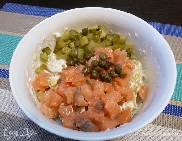 Теперь добавим нарезанные кубиком маринованные огурцы и малосольную форель, каперсы. 