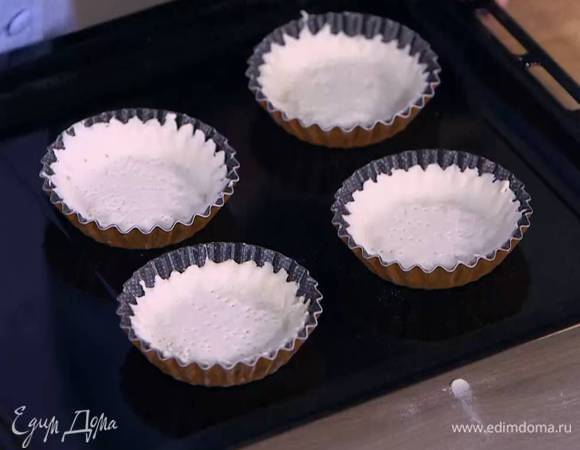 Формочками для тарталеток вырезать из теста кружки, выложить их в формочки, так чтобы получились бортики, и часто наколоть вилкой.