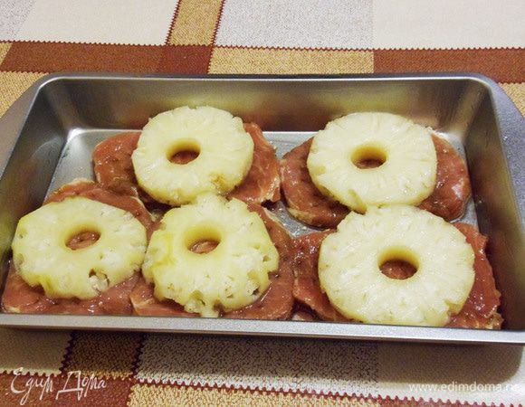 Форму немного смазать маслом. Кусочки свинины выложить в форму. Можно посолить, поперчить по вкусу. Сверху выложить кольца ананасов.