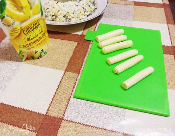 Для свечей воспользуемся пластинками сыра для бутербродов. Аккуратно скатать в трубочку и установить равномерно в кольцо. 