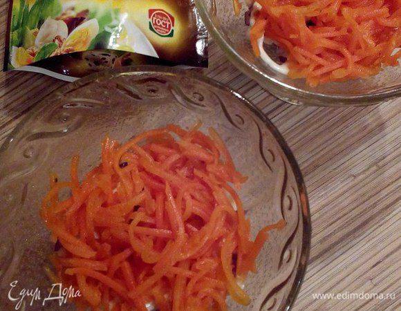 Далее уложите слой морковки по-корейски. Если ее полоски слишком длинные, то ее лучше измельчить.