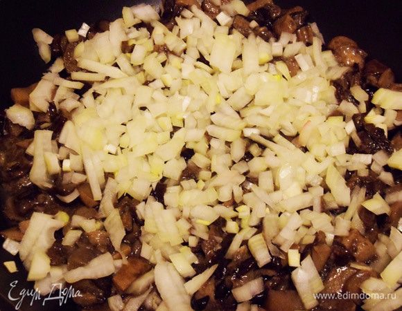На сковороду налить совсем немного растительного масла. Грибы и половину лука обжарить, помешивая, примерно 10 минут после выпаривания жидкости.