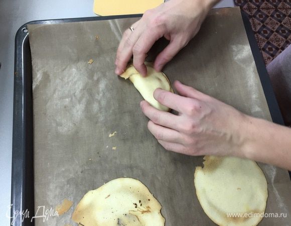 Достаете печенья, переворачиваете их лопаткой. Тут же берете бумажку, кладете в середину печенья и нежно сгибаете пополам, соединяя края.