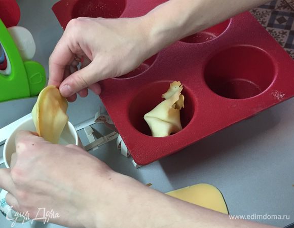 Придерживая края согнутого печенья, быстро нажимаете сгибом на край чашки, чтобы согнуть его еще раз, и опускаете готовое печенье в пустую ячейку формы для маффинов. Там оно окончательно остынет и уже форму не потеряет. А вы, не мешкая, гните следующее печенье!