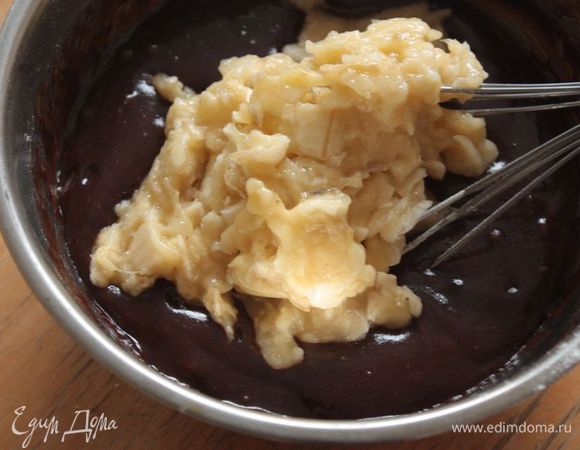 Тщательно разомните банан вилкой и вмешайте в тесто. Обваляйте изюм и грецкие орехи в муке, добавьте в тесто и размешайте, чтобы они равномерно там распределились.