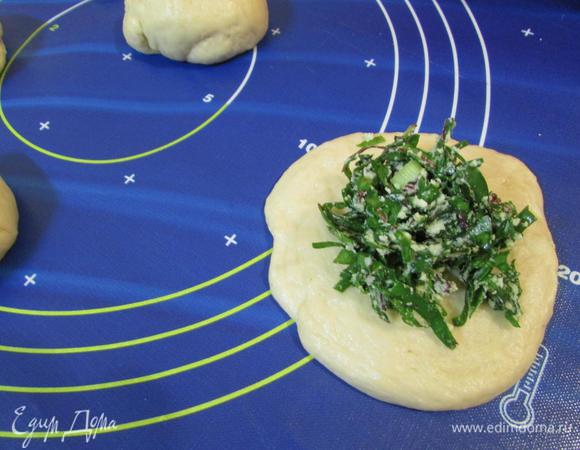 Подошедшее тесто разделить на равные кусочки (у меня по 50 грамм, 16 штук). Каждый кусочек прижать ладонью, чтобы образовалась лепешка. Выложить на середину начинку. 