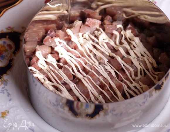 Начинаем собирать торт. Ставим на тарелку самое большое кольцо и укладываем сельдь. Сверху майонез сеточкой.