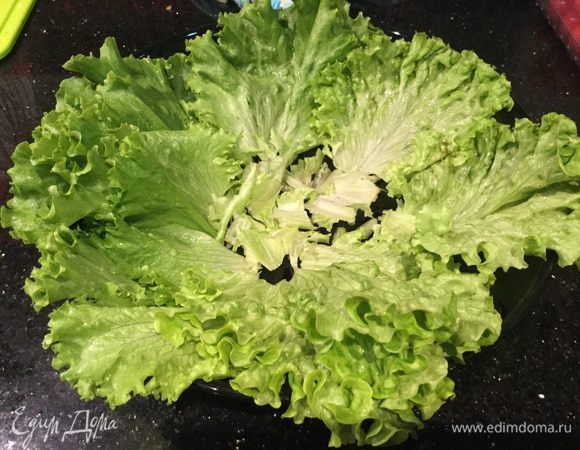 Листья салата вымойте, обсушите бумажным полотенцем и выложите в салатник.