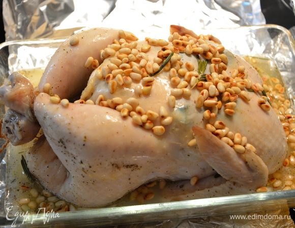Через час снять фольгу, сверху выложить жареные кедровые орешки и добавить куриный бульон. Выпекать при 225°С до золотистой корочки, примерно 30 — 40 минут, 2 — 3 раза переворачивать.