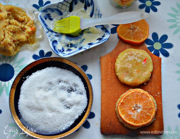 Достаньте из морозилки охлажденное тесто. Отщипывая кусочки, сформируйте небольшие шарики. Каждый шарик примните сверху руками или с помощью стакана. Размер полученных «лепешек» должен быть чуть больше мандариновых долек. 