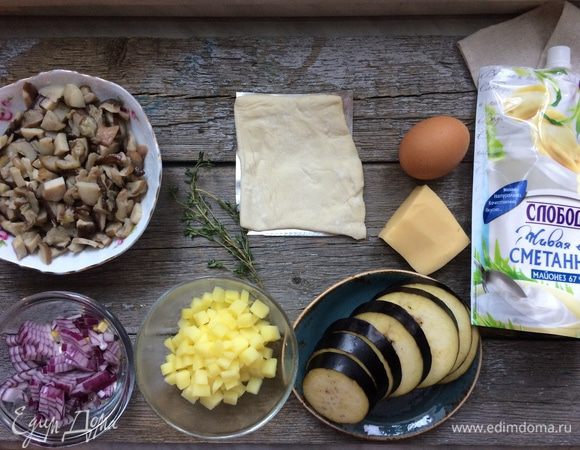 Разогрейте духовку до 180°С. Картофель очистите, нарежьте на кубики и отварите в подсоленной воде до полу готовности. Воду слейте. Баклажан нарежьте на кружочки толщиной 5 мм. Лук очистите и мелко нарежьте. Грибы разморозить и мелко нарезать. 