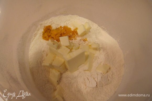 Просеянную муку перемешать с сахаром, разрыхлителем, содой, солью и цедрой апельсина. Добавить порезанное на кусочки холодное сливочное масло.