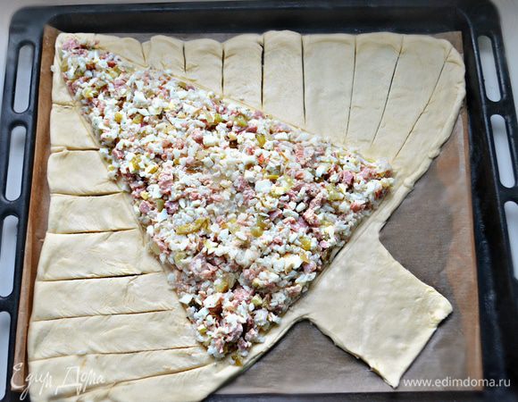 Выложите начинку, по краям с помощью ножа сделайте надрезы. Взбейте в отдельной емкости яйцо и с помощью кисточки смажьте тесто немного яйцом.