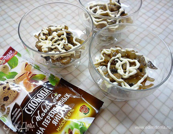 В порционные салатники слоями укладываем: первым слоем — грибы с луком, промазываем майонезом ТМ «Слобода» На перепелиных яйцах.