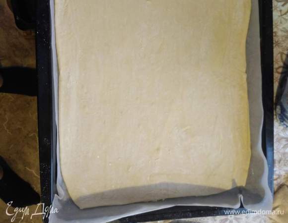 На противень кладем сначала лист пергамента, затем выкладываем раскатанное тесто.