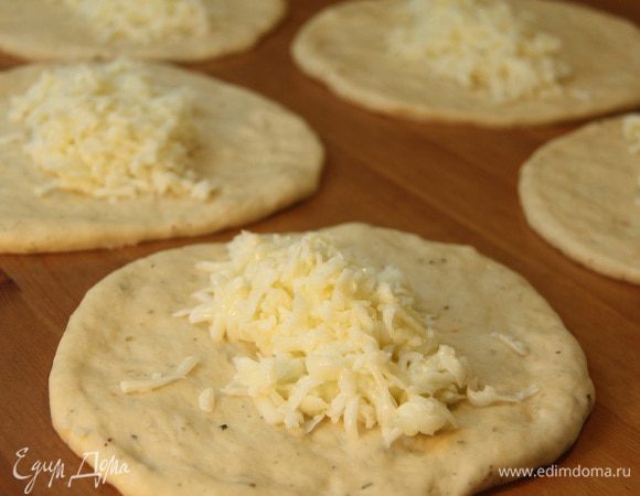 Каждый кусок раскатать в лепешку диаметром примерно 12 —  15 см, выложить в центр начинку из сыра и белков.