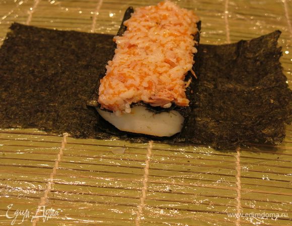 Кладем кальмар поперек на половинку листа нори (кусочек 1). Выкладываем на него рис, тщательно заполняя полости в «зубцах скорлупы».