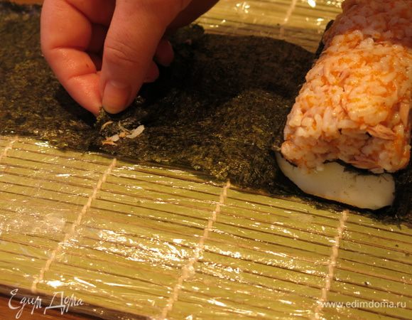 Вся конструкция должна была поместится в лист нори  длиной 19 см, высотой 10,5 см, но мне нори немного не хватило. Поэтому удлиняем лист нори, на край кладем полоску риса, по несколько рисинок в место соединения листов и на нее лист нори.