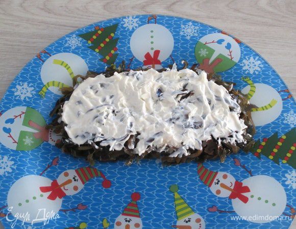 Мелко нашинкуйте репчатый лук, уложите его поверх морской капусты и сопроводите слоем из половины майонеза.