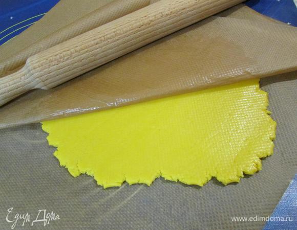 Достать тесто из холодильника и раскатать между двумя листами пергамента.