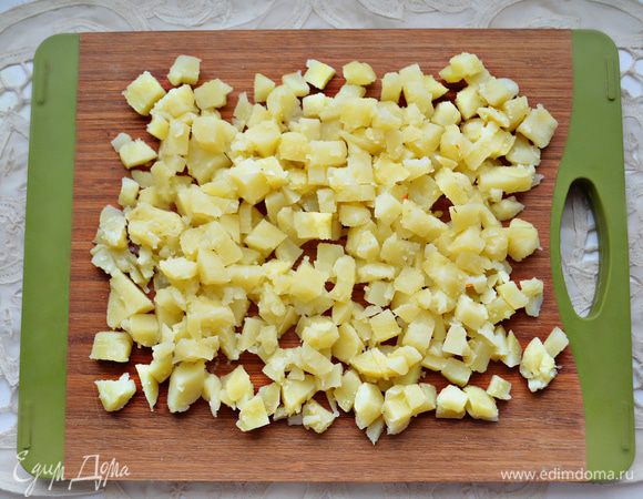 Картофель отварите «в мундире» до готовности, охладите, почистите и нарежьте кубиками.