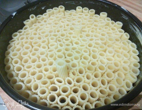 Параллельно отварить ригатони. Отварить пасту нужно до половины времени, указанного на упаковке. Это важно! Откинуть на дуршлаг, дать стечь жидкости. Разъемную форму 21 — 22 см в диаметре смазать маслом и наполнить ригатони. Раскладывать ригатони нужно в вертикальном положении, форму для этого удобно наклонить. Паста должна стоять плотно друг к другу. 