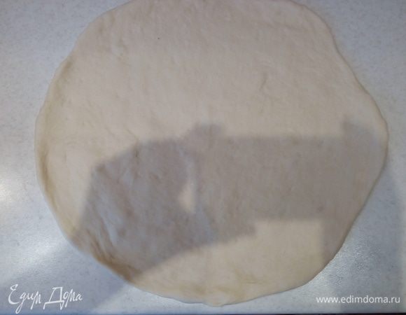 Обминаем тесто, отделяем 3/4 от всего теста и раскатываем эту часть с помощью скалки в круг.