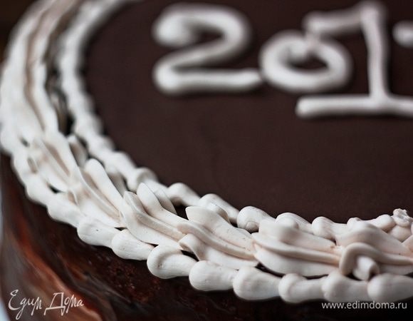 Достаем торт из холодильника и поливаем сверху глазурью. Также смазываем ею бока торта. С помощью кондитерского мешка украшаем торт кремом. При желании можно украсить бока шоколадной крошкой, а оставшейся глазурью нарисовать те самые «гусиные лапки». 