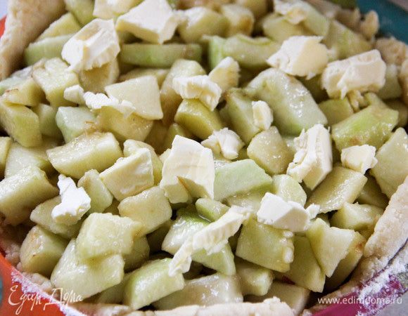 Переносим пласт в форму для выпечки и выкладываем начинку. Поверх нее кладем кусочки холодного масла. 