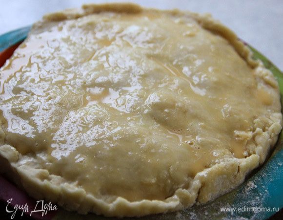 Разогреваем духовку до 210°С. Достаем пирог, делаем аккуратные надрезы сверху. Смазываем смесью яйца с 1 ч. л. воды. Ставим в духовку на 20 минут. Затем снижаем температуру до 160°С и выпекаем еще 40 минут.