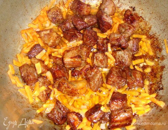 К обжаренному мясу выложить морковь, перемешать и обжарить пару минут.