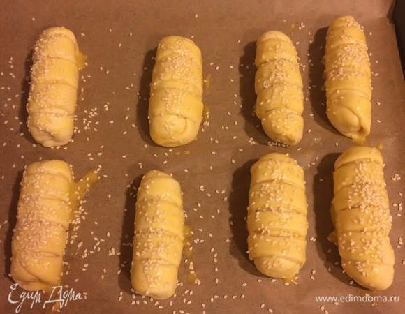 Булочки выложить на противень. Желток смешать с молоком. Смазать булочки и посыпать кунжутом.