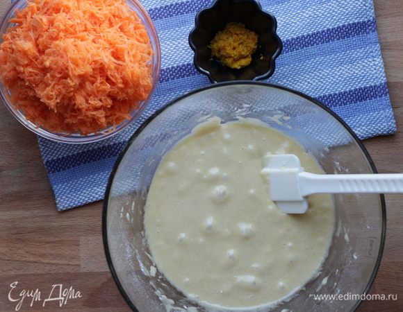 Замесить тесто силиконовой лопаткой: влить в муку яично-сахарную смесь. Затем добавить морковь с цедрой и тщательно перемешать лопаткой.