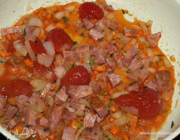 Лук, морковь, половину петрушки мелко шинкуем. Сковороду разогреваем, добавляем растительное масло и обжариваем овощи, пока лук не станет прозрачным. Колбасу режем кубиками и добавляем к овощам. Обжариваем минуты 2 — 3 и добавляем помидоры в собственном соку (предварительно снимаем кожицу). Помидоры можно нарезать или же отправить в сковороду целиком, а в процессе готовки размять. Потушить минут 5 — 7 и добавить оставшуюся зелень и мелко порубленный чеснок, соль, перец по вкусу. Томим 1 минуту. 