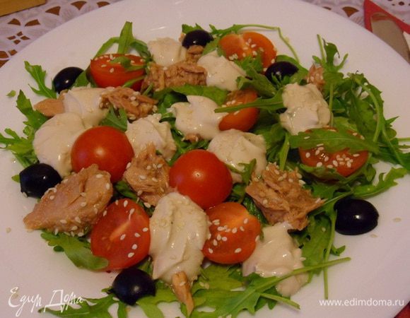 Выложить салат на тарелки. Сверху уложить кусочки тунца, чайной ложкой полить соусом. Присыпать для украшения кунжутом. Можно добавить половинки маслин.