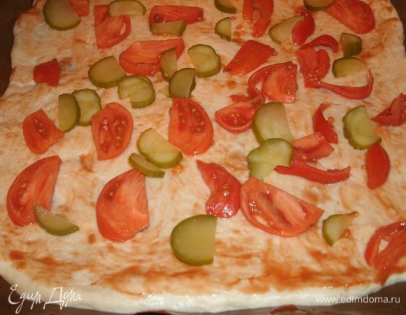Раскатать половину теста тонким слоем (у меня противень небольшой, поэтому из этого количества продуктов делаю 2 пиццы), смазать кетчупом, разложить нарезанные огурцы и помидоры. 