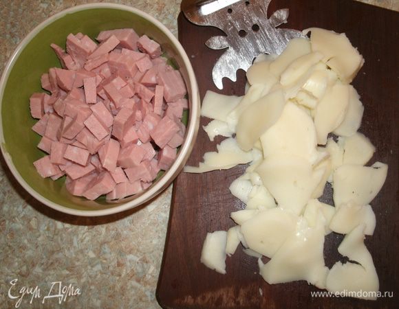 Вареную колбасу нарезать мелкими кубиками, сыр — пластинками (лучше сделать это сырорезкой).
