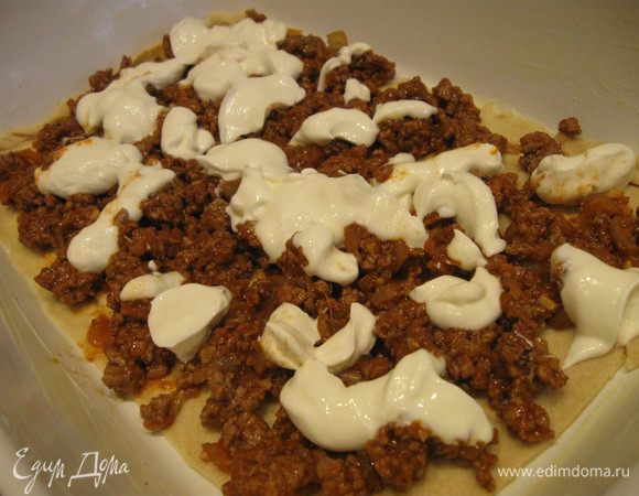 Рабочую поверхность припылить мукой и раскатать каждую пластину теста под размер формы, смазать форму сливочным маслом. Духовку разогреть до 200°С. Положить 1 пласт в форму. 
Выложить немного ягнятины, распределить по поверхности несколько капель йогурта. (У меня в общей сложности получилось 3 слоя ягнятины, которые перемежались тестом и 2 слоями баклажанов).