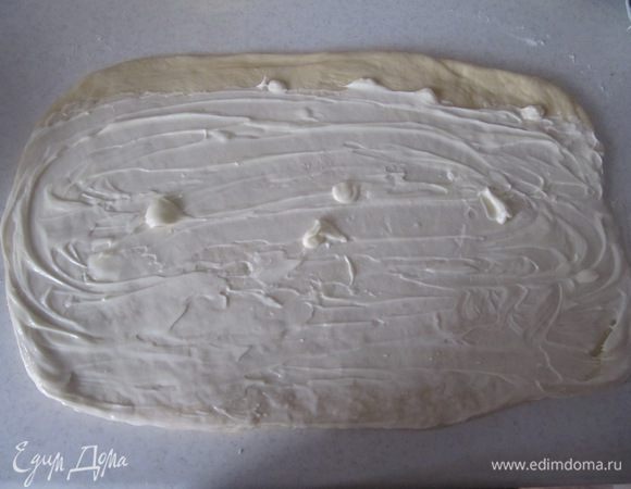 Распределить по поверхности теста размягченное сливочное масло, оставив полоску шириной около 1 см по длинной стороне.