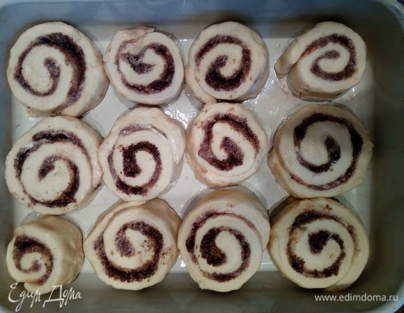 Получившийся рулет разрезать на 12 приблизительно одинаковых кусочков. Выложить их в смазанную растительным маслом форму не вплотную друг к другу. Накрыть форму пищевой пленкой и оставить на расстойку на 30 минут.