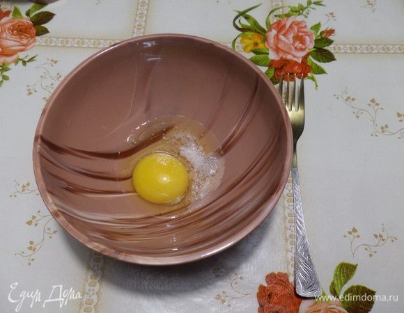 В чашку разбиваем яйцо. Добавляем щепотку соли и щепотку сахара. Взбиваем.