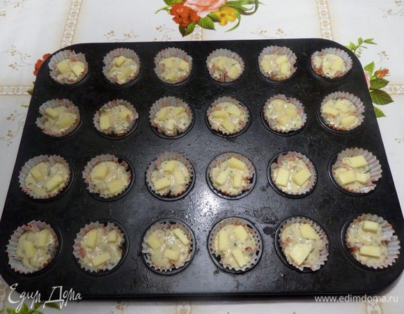 Выкладываем тесто в формы для кексов. Добавляем нарезанный сыр, слегка вдавливая его в тесто. Ставим формы в разогретую духовку и выпекаем 12 — 15 минут при 180°С. (Ориентируйтесь на свою духовку и размеры форм, в которых будете выпекать).