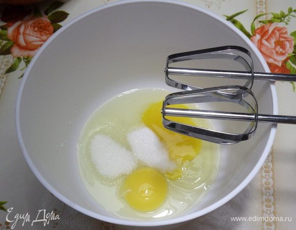В чашу разбиваем куриные яйца. Добавляем соль и сахар. Взбиваем миксером.