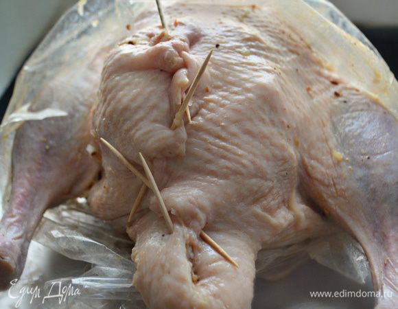 Наполните утку начинкой и закрепите отверстие зубочистками. Поместите тушку в рукав для запекания, сделайте в 3 — 4 местах проколы в рукаве и поставьте противень с уткой в разогретую до 180°С духовку. Через 1,15 ч. аккуратно раскройте рукав. Разложите вокруг утки яблочки (предварительно наколите их нескольких местах зубочисткой), разрезанную пополам головку чеснока и запекайте еще около 1 часа, периодически поливая утку  выделившимся соком.