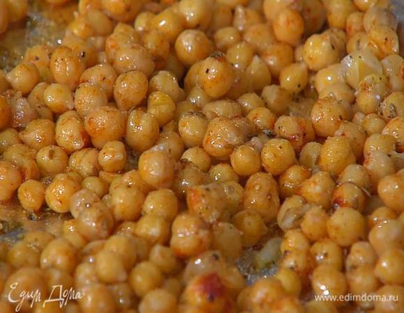 Отваренный нут выложить на противень, выстеленный фольгой, высыпать сверху сухой чеснок, зиру, 1 ч. ложку паприки, по 1/4 ч. ложки молотого имбиря и кардамона, слегка посолить, поперчить, полить оливковым маслом и перемешать.