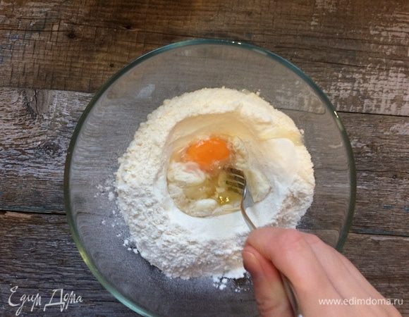 С помощью вилки начните собирать тесто так, чтобы вода и яйцо не выливались из углубления.