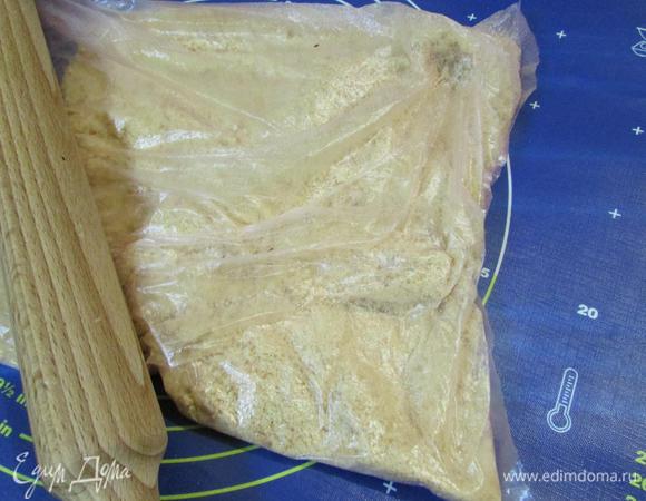 Приготовить основу для тарта. Печенье сложить в пакет и с помощью скалки, раздробить в мелкую крошку. Крошку переложить в миску.