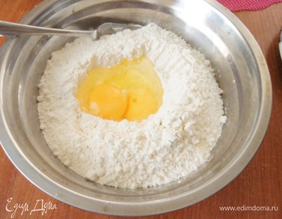 Муку просеять в миску, сделать углубление и влить желток и яйцо, немного присолить.