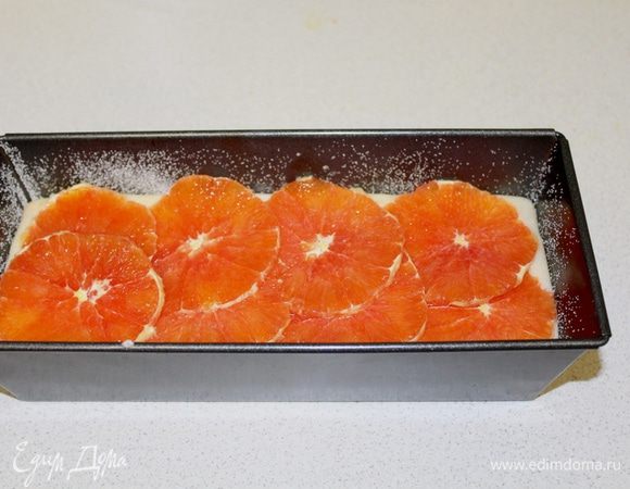 Апельсины очистить от кожицы, порезать кружочками и выложить поверх теста.