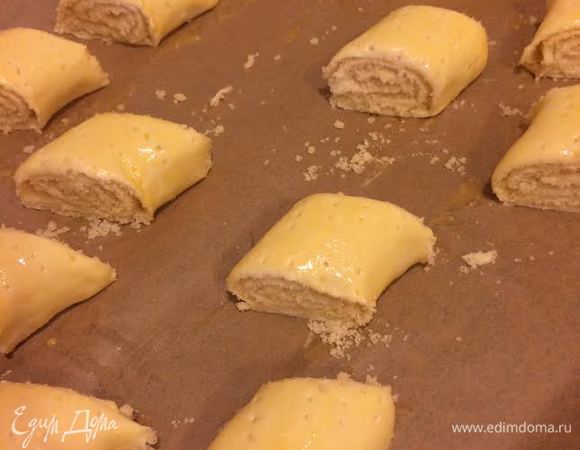 Желток смешать с молоком, смазать им рулеты. Затем рулеты наколоть вилкой и разрезать острым ножом на порционные куски. Выложить на противень. Я рулеты смазываю и режу прямо на противне, так как тесто очень нежное и его потом тяжело переносить.